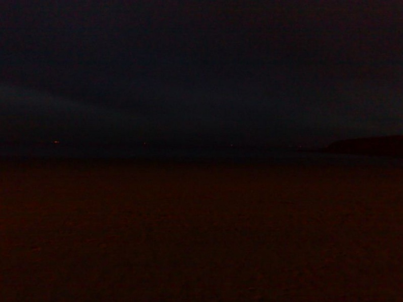 The sky and beach seperated by a shoreline in the dark!