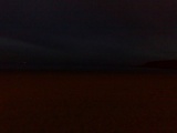 The sky and beach seperated by a shoreline in the dark!