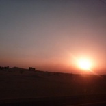The desert sand gives the sunset a distinctive orange hue