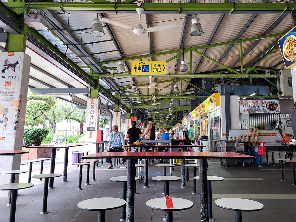 Socially distanced hawker center with iconic crossed out seats reminding you of 2020